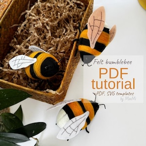 May include: Handmade felt bumblebees with black and yellow striped bodies and white wings are displayed near a woven basket. The image includes text that reads "Felt bumblebee PDF tutorial" with "PDF, SVG templates by MiniMi".