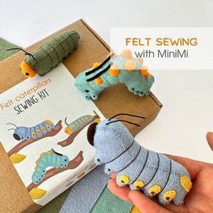 May include: A felt sewing kit in a cardboard box featuring illustrations of caterpillars and the text "FELT SEWING with MiniMi" and "felt caterpillars SEWING KIT". Three plush felt caterpillars in green, light blue, and teal are included.