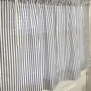 May include: White and black striped curtain panels. The curtains are made of a lightweight fabric and are hung on a rod. The stripes are vertical and evenly spaced. The curtains are partially covering a window with blinds.