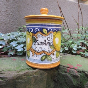 May include: A yellow ceramic canister with a blue and white design featuring lemons and the word "Zucchero" (Italian for sugar).