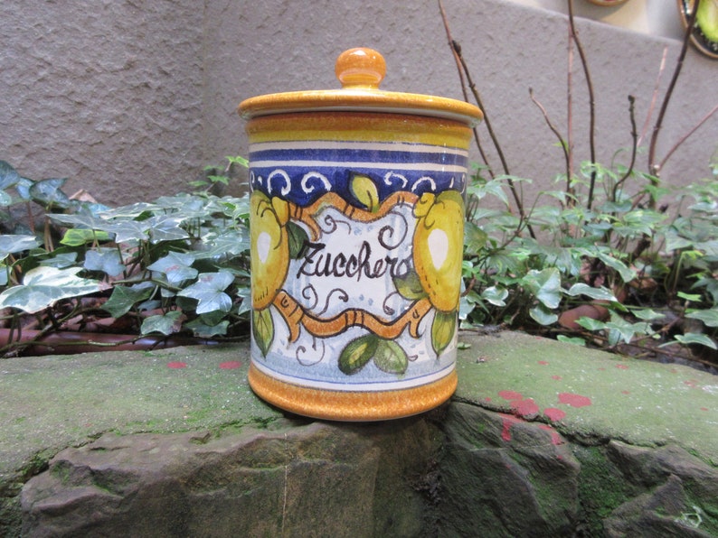 May include: A yellow ceramic canister with a blue and white design featuring lemons and the word "Zucchero" (Italian for sugar).
