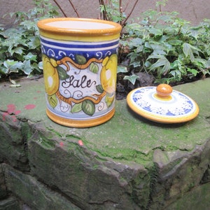May include: A ceramic salt jar with a yellow, blue, and white design featuring lemons and the word "Sale". The jar has a matching lid with a knob.