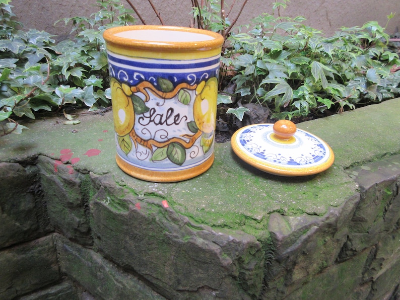 May include: A ceramic salt jar with a yellow, blue, and white design featuring lemons and the word "Sale". The jar has a matching lid with a knob.