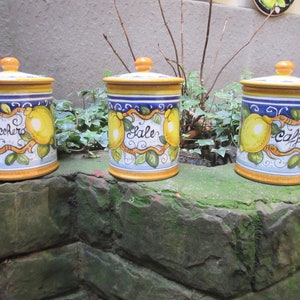 Puede incluir: Tres botes de cerámica con diseños amarillos, azules y blancos. Los botes tienen tapas y están decorados con limones y las palabras "Zucchero", "Sale" y "Caffe".