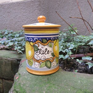 May include: A yellow, blue, and white ceramic jar with a lid. The jar has a lemon design and the word "Sale" written on it.