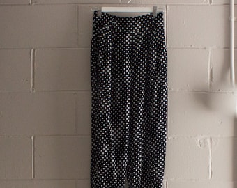 Puede incluir: Pantalón negro con lunares blancos, cintura alta y corte holgado.