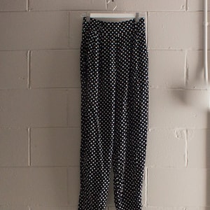 Puede incluir: Pantalón negro con lunares blancos, cintura alta y corte holgado.