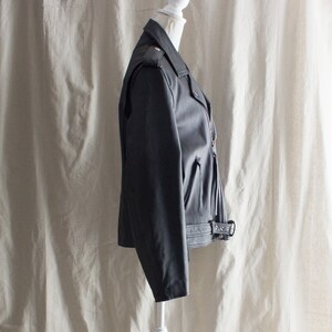 May include: A black leather motorcycle jacket with a zipper closure and a belt at the waist.