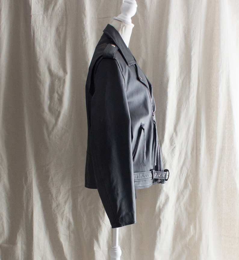 May include: A black leather motorcycle jacket with a zipper closure and a belt at the waist.