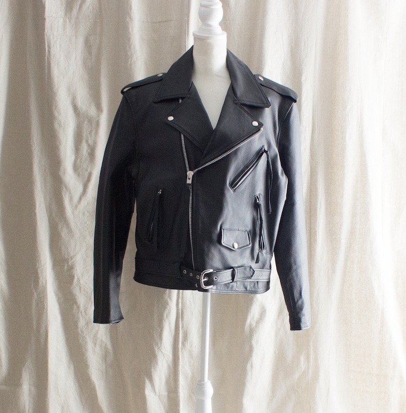 May include: A black leather motorcycle jacket with a zipper closure, a belt, and fringe details.