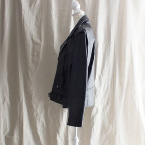 May include: A black leather jacket with a zipper closure and a belt at the waist.