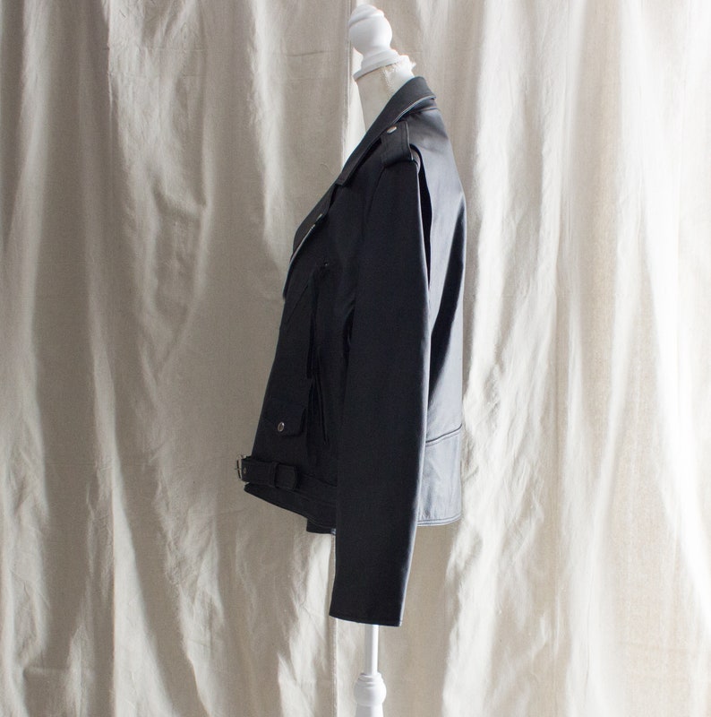May include: A black leather jacket with a zipper closure and a belt at the waist.