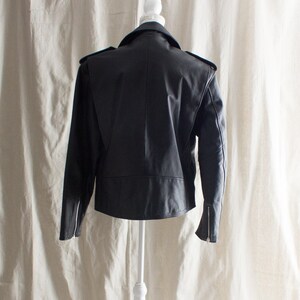 May include: Black leather jacket with a zipper closure and a stand-up collar.