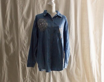 May include: A light blue denim shirt with embroidered details. The shirt has a button-down front and long sleeves.