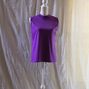 以下が含まれることがあります： 白い背景に白いマネキンに置かれた紫色のノースリーブシャツ