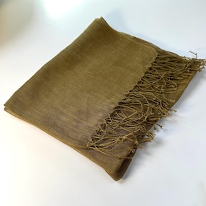 May include: Olive green scarf with a fringed edge. The scarf is made of a soft, woven material and is folded over on itself. The fringe is a lighter shade of olive green. The scarf is displayed on a white surface.