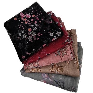 May include: A stack of five floral patterned scarves in various colours, including black, red, pink, beige, and grey. The scarves are made of a soft, lightweight fabric and feature a delicate floral design.
