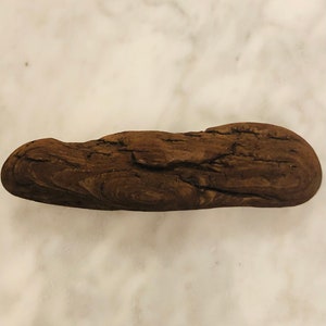 May include: A dark brown piece of driftwood with a smooth, rounded surface and a natural, weathered texture.