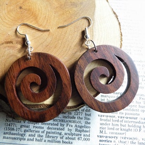 May include: A pair of wooden earrings with a spiral design. The earrings are brown and have silver hooks.