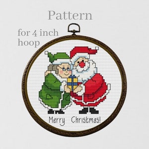 May include: Cross stitch pattern for a 4 inch hoop featuring Santa Claus and a woman in a green dress holding a gift. The pattern includes the text "Merry Christmas!"
