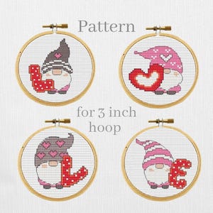 Könnte beinhalten: Vier Kreuzstichmuster in Holzreifen mit Zwergen. Jeder Zwerg hat einen anderen Hut und hält ein Herz oder das Wort "LOVE" in Rot. Der Text "Pattern for 7.6 cm hoop" ist ebenfalls sichtbar.