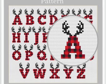 May include: A cross-stitch pattern featuring the alphabet from A to Z. Each letter is rendered in a red and black buffalo plaid design, topped with a pair of black antlers. A circular magnifying overlay highlights the letter A in detail.