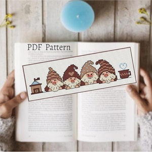 May include: A PDF pattern for cross-stitching a bookmark featuring four gnomes with brown hats and beards, a small house, and a cup of coffee. The pattern is printed on a white background.
