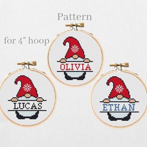 May include: Three cross-stitch patterns for a 4-inch hoop featuring a gnome holding a sign with a name. The gnomes are wearing red hats with white snowflakes and have white beards. The names on the signs are Olivia, Lucas, and Ethan.