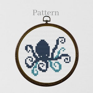 Könnte beinhalten: Ein schwarzes und blaues Kreuzstichmuster eines Kraken mit blauen Wirbeln drumherum, gerahmt in einem braunen Holzreifen. Das Wort "Pattern" steht über dem Reifen.