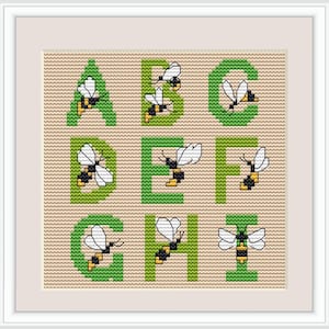 May include: Cross-stitch alphabet sampler featuring the letters A through I in green, each with a bee design. The bees have white wings and black and yellow bodies. The background is a light tan color.