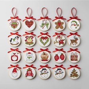 May include: A collection of 20 Christmas ornament cross-stitch designs. Each circular ornament features a festive image, including a gingerbread man, Santa, and a Christmas tree. They are framed in wooden hoops and have red ribbon hangers.
