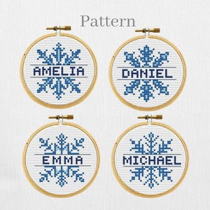 Puede incluir: Cuatro aros de bordado con diseños de copos de nieve y los nombres Amelia, Daniel, Emma y Michael.