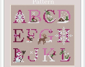 May include: A cross-stitch pattern featuring the alphabet in pink with winter-themed illustrations. The letters are A, B, C, D, E, F, G, H, I, J, K, and L. Each letter has a different illustration, such as a snowflake, a snowman, a reindeer, and a bird.