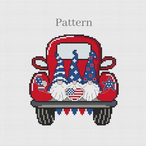 May include: Three gnomes in a red pickup truck with American flag decorations. The gnomes are wearing red, white, and blue hats and have white beards. The truck has a white heart with an American flag design on the back.