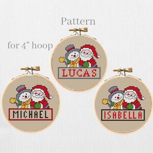 May include: Three 4-inch embroidery hoops with cross-stitch patterns of a snowman and Santa Claus. The hoops are labeled "Lucas", "Michael", and "Isabella".