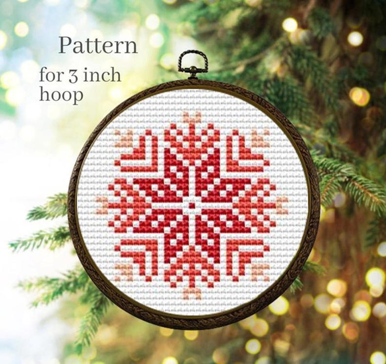 Puede incluir: Un patr&oacute;n de punto de cruz en un bastidor de 7,6 cm. El dise&ntilde;o presenta un copo de nieve rojo y blanco. El texto "Pattern for 3 inch hoop" es visible en la imagen. El bastidor tiene un marco de madera marr&oacute;n oscuro.