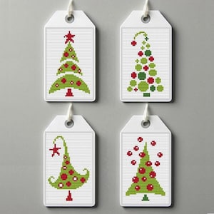 May include: Four white gift tags with different green and red Christmas tree designs. The trees are decorated with red ornaments and a star.
