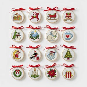 Pode incluir: Dezasseis enfeites de Natal com desenhos de ponto cruz em aros de madeira. Os desenhos incluem uma casa, rena, trenó, soldado, boneco de neve, pássaro, urso, caneca, lua, pássaro, Papai Noel, árvore, grinalda, vela, poinsétia e presente. Com fita vermelha.