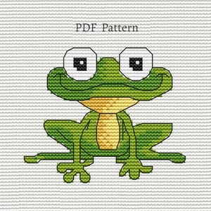 Può includere: Un modello a punto croce di una rana verde con grandi occhi quadrati e una pancia gialla. La rana è su uno sfondo bianco. Il testo "PDF Pattern" è sopra la rana.