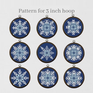 Puede incluir: Nueve patrones de bordado en forma de copo de nieve azul y blanco. Los aros tienen un diámetro de 7,6 cm. "Pattern for 3 inch hoop" está escrito en la parte superior de la imagen.