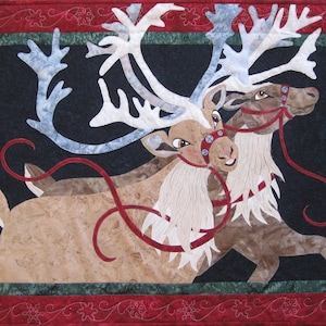 May include: Two brown and white reindeer with large antlers are pulling a red ribbon against a black background. The reindeer are wearing red harnesses with silver buckles. The image is framed with a red and green border.