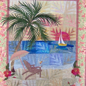 May include: A colorful quilt depicting a tropical beach scene with a palm tree, a sailboat, a lounge chair, and a cocktail. The quilt is framed with a pink and green floral border.