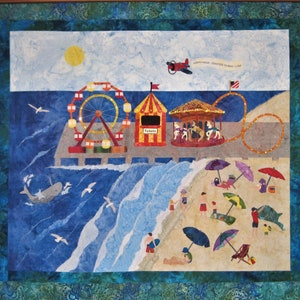 May include: A colorful quilted wall hanging depicting a beach scene with a Ferris wheel, carousel, and people on the beach. The sky is blue with a yellow sun and a red airplane. The text "Happy Hour - Dockside Tavern - 5 PM" is visible in the upper right corner.