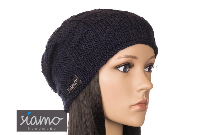 Peut inclure: Un bonnet en tricot bleu marine avec une petite &eacute;tiquette noire qui dit "siamo handmade".