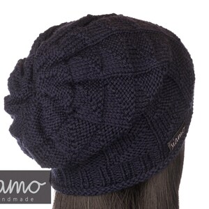 Peut inclure: Un bonnet en tricot bleu fonc&eacute; avec un motif en c&ocirc;tes. Le bonnet a une coupe ample et une petite &eacute;tiquette avec le mot "siamo" sur le c&ocirc;t&eacute;.