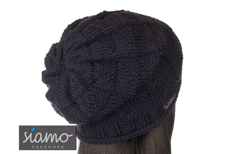 Peut inclure: Un bonnet en tricot bleu fonc&eacute; avec un motif en c&ocirc;tes. Le bonnet a une coupe ample et une petite &eacute;tiquette avec le mot "siamo" sur le c&ocirc;t&eacute;.