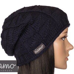 Peut inclure: Un bonnet en tricot bleu marine &agrave; la coupe ample. Le bonnet porte une petite &eacute;tiquette avec le texte "siamo handmade" sur le c&ocirc;t&eacute;.