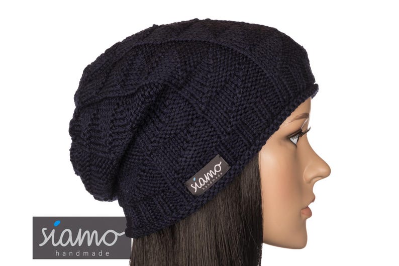 Peut inclure: Un bonnet en tricot bleu marine &agrave; la coupe ample. Le bonnet porte une petite &eacute;tiquette avec le texte "siamo handmade" sur le c&ocirc;t&eacute;.