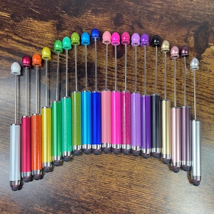 May include: A collection of colorful stylus pens arranged in an arc. Each pen features a metallic body in various colors, including silver, red, orange, yellow, green, blue, pink, purple, and black. The pens have a silver tip and a matching colored top.