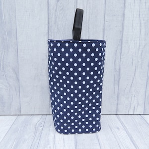 Puede incluir: Un contenedor de almacenamiento de tela azul y blanco con lunares y un asa negra.